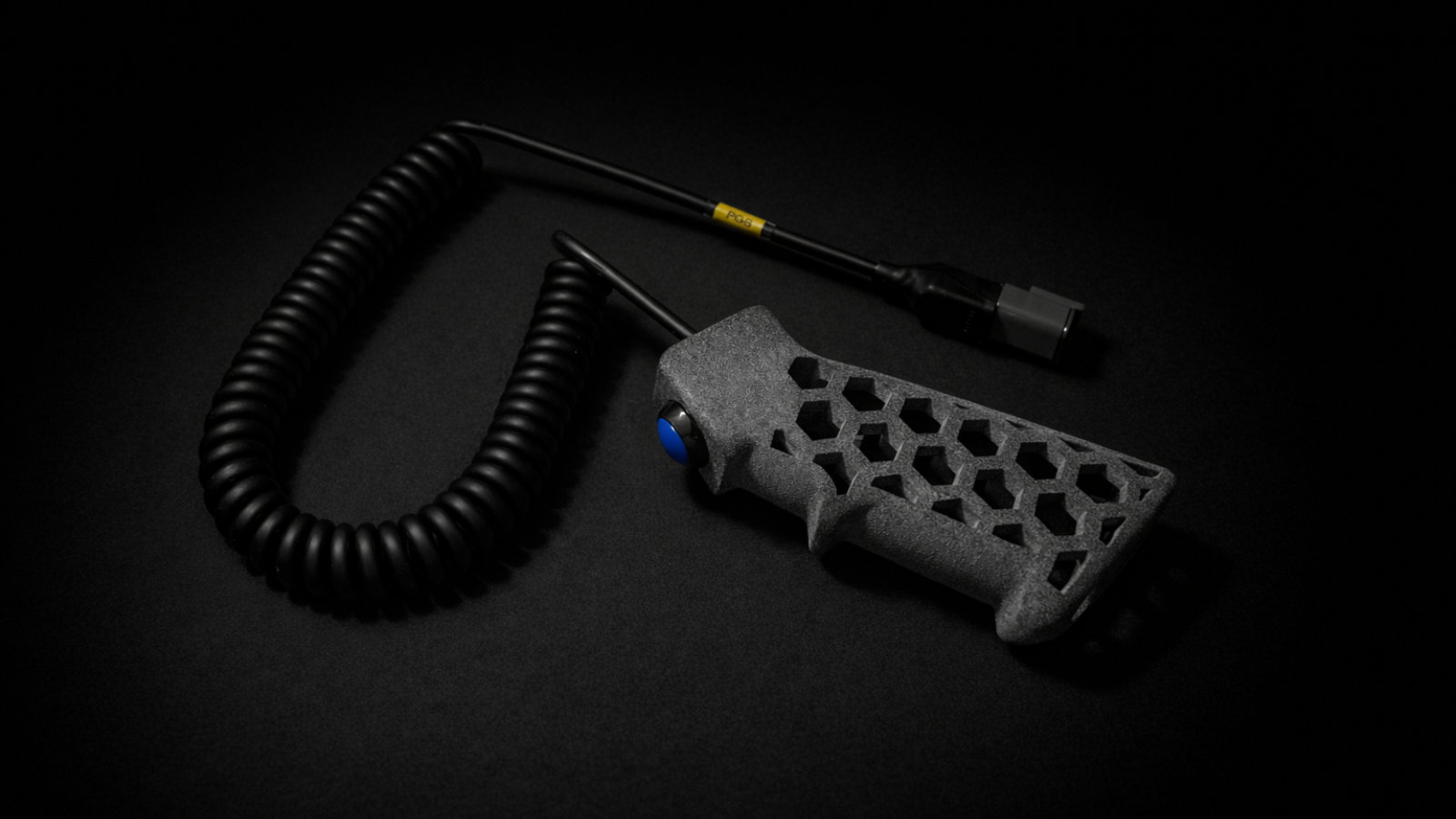 XVIA PGB pistol grip trigger with coiled cable and connector on a dark surface