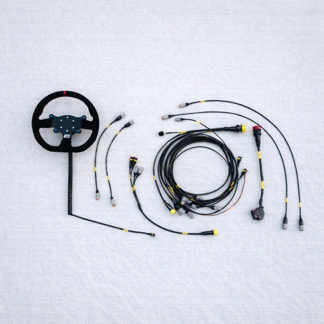 Steering wheel and completed motorsport wiring harness package prepared for off-road race integration